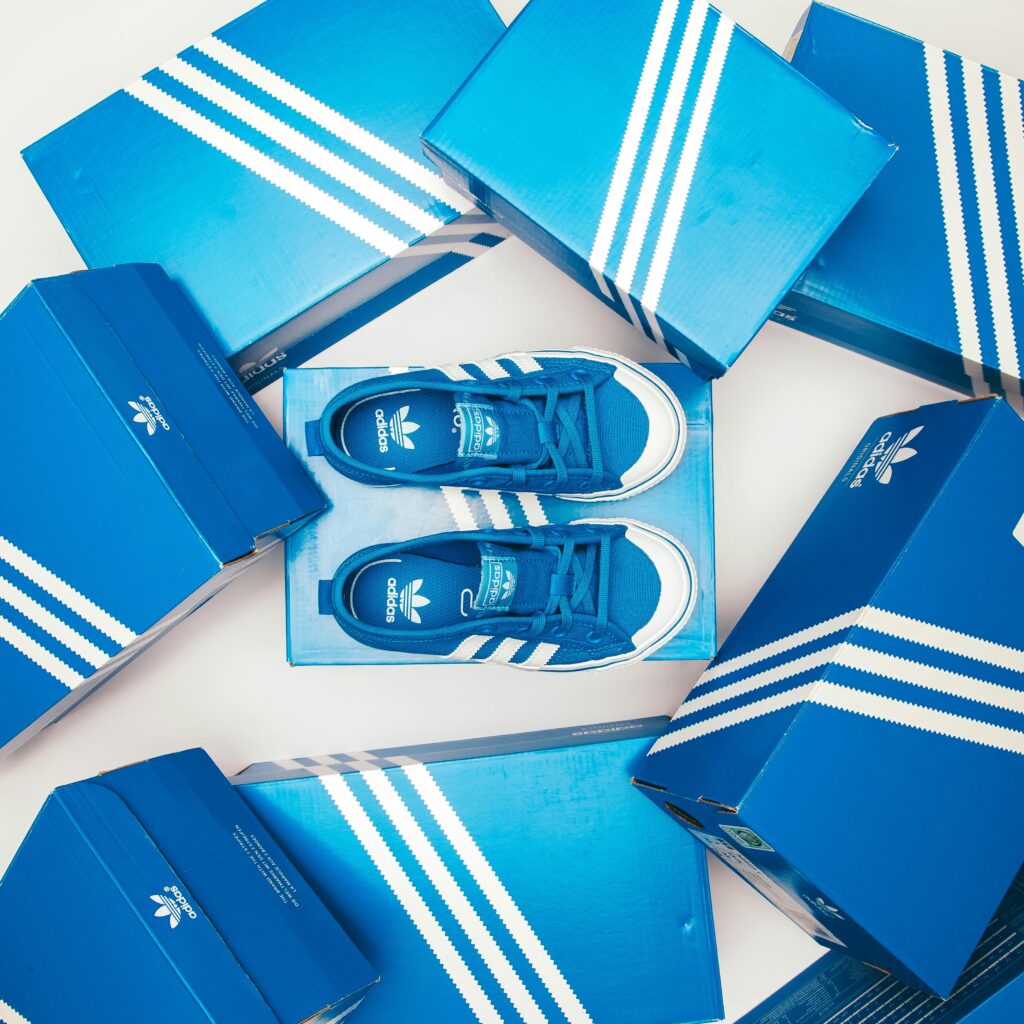 Blue Adidas shoes and boxes arranged in a stylish flat lay on a white background.