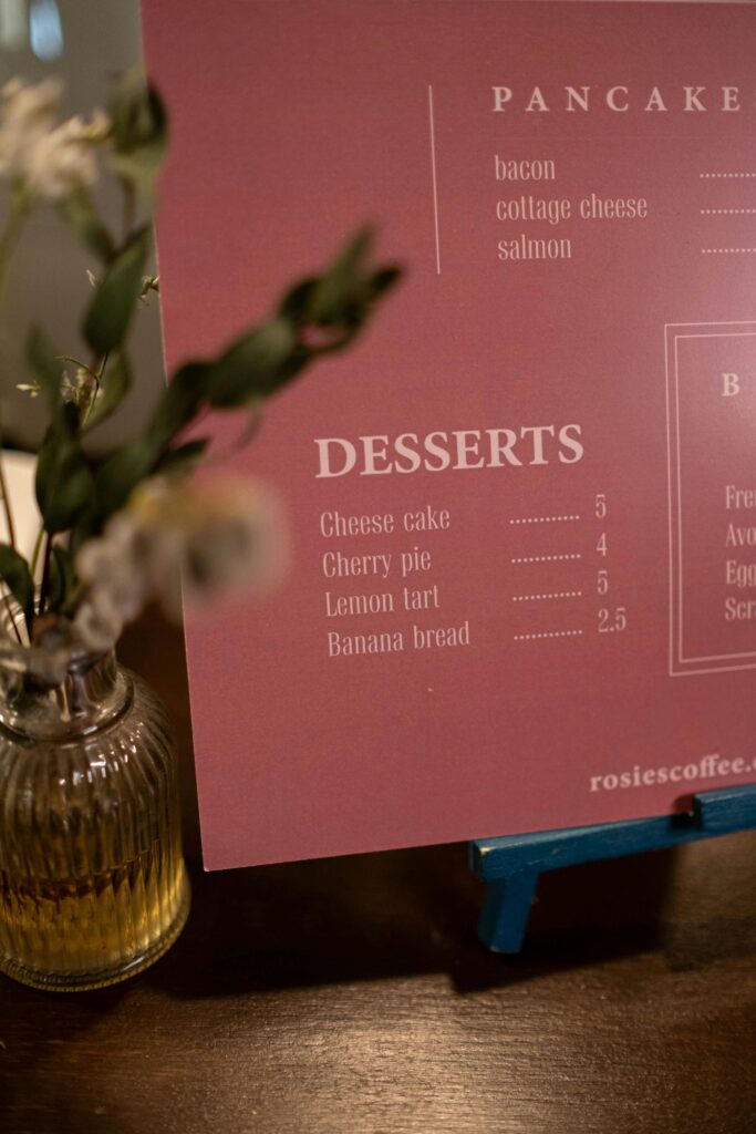 A stylish café menu showing dessert options next to a decorative vase.
